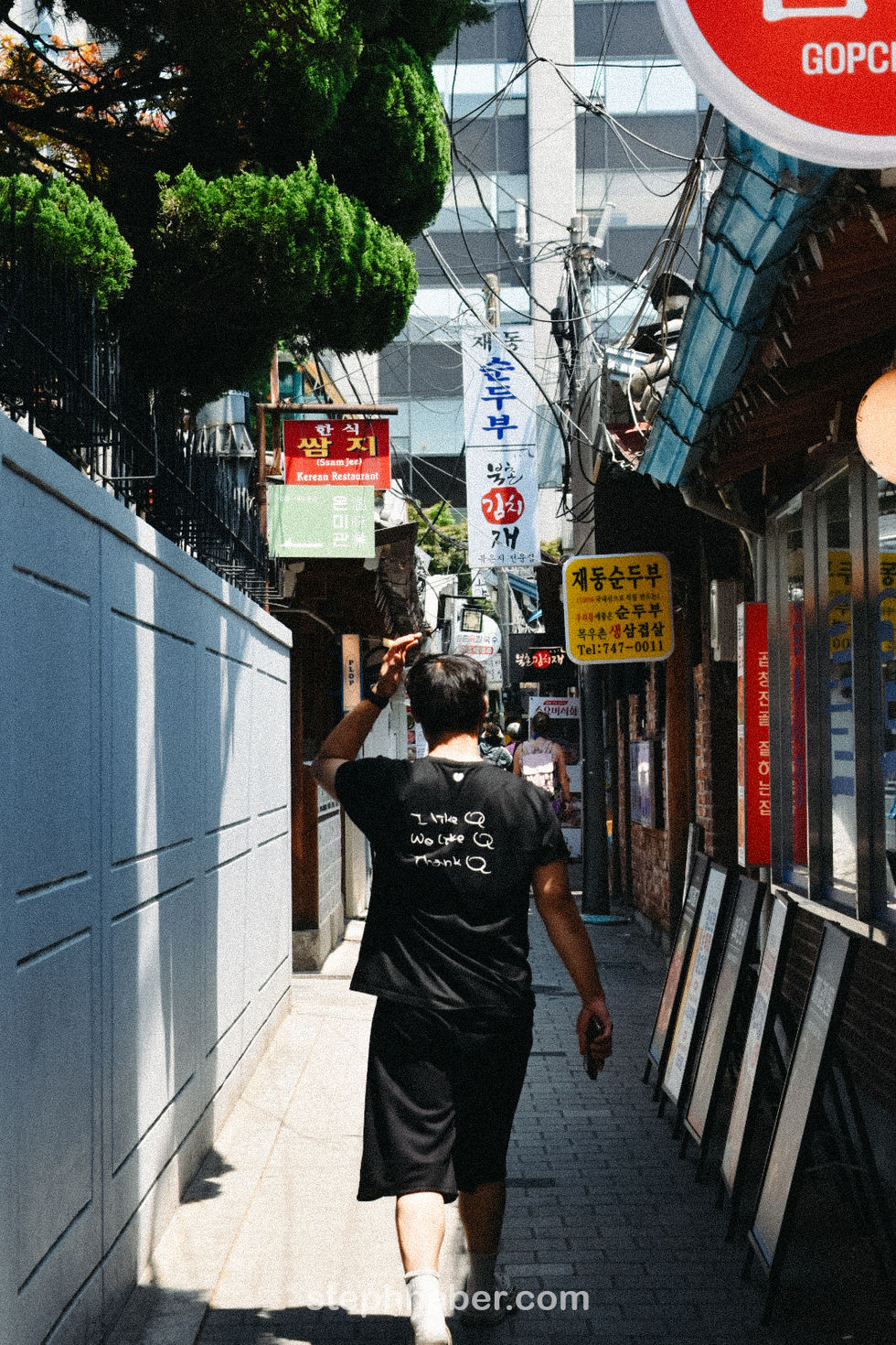 Person walking down narrow alley with signs overhead.