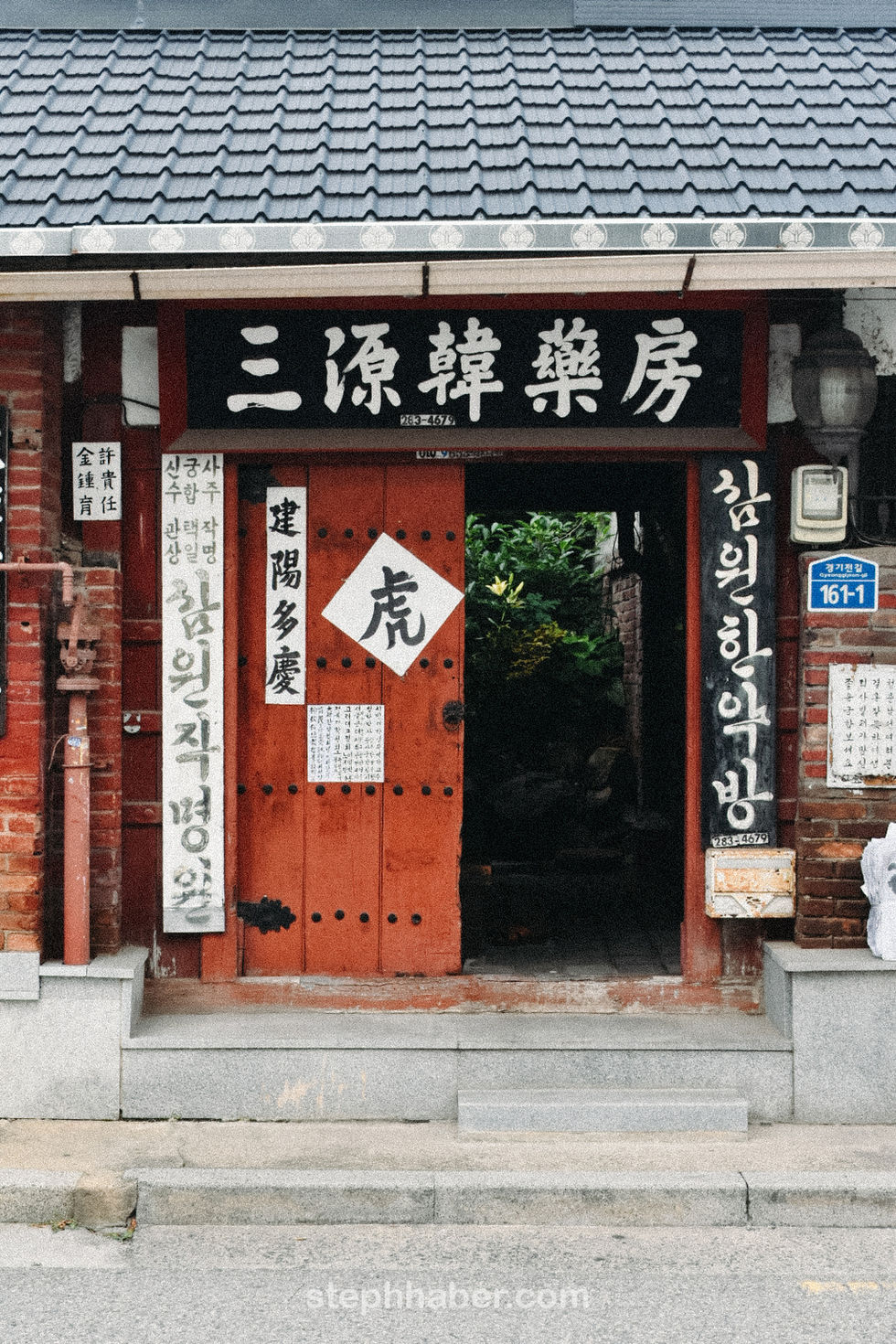 Traditional Korean building entrance with wooden door and signs.