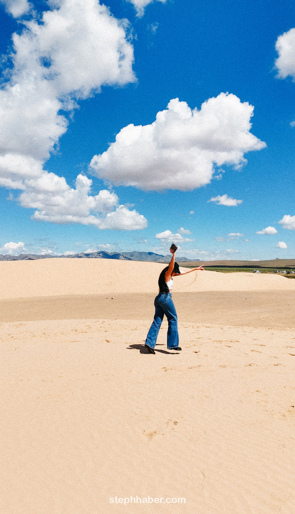Person standing on sand dunes under blue sky. Mongolia
