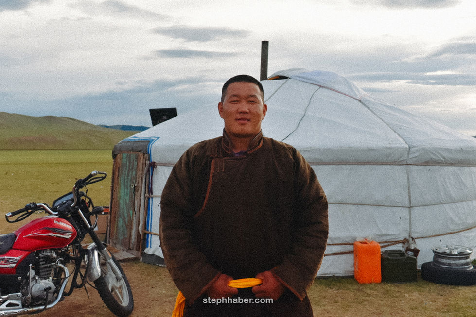 Man standing in front of a yurt, holding object.