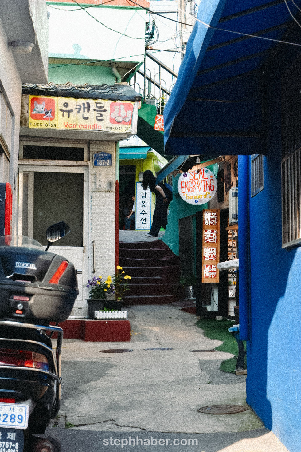 Narrow alley with colorful signs and a staircase.