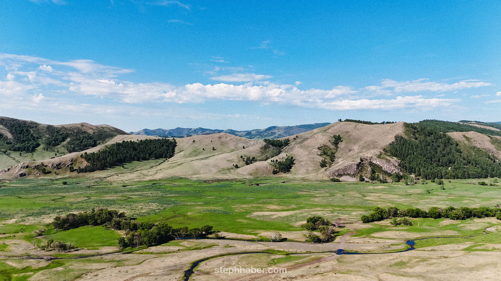 Rolling hills and green valley under blue sky.