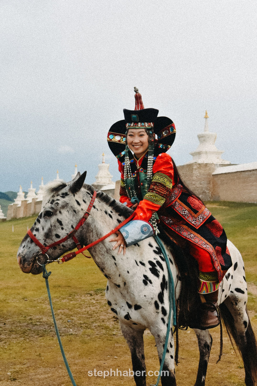 Person in traditional attire riding a spotted horse.