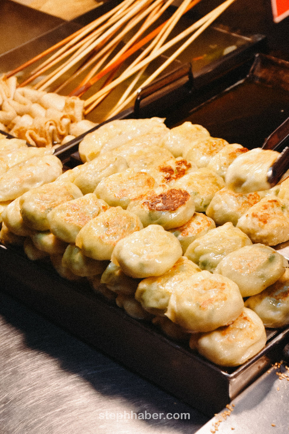 Golden-brown dumplings stacked on a grill.