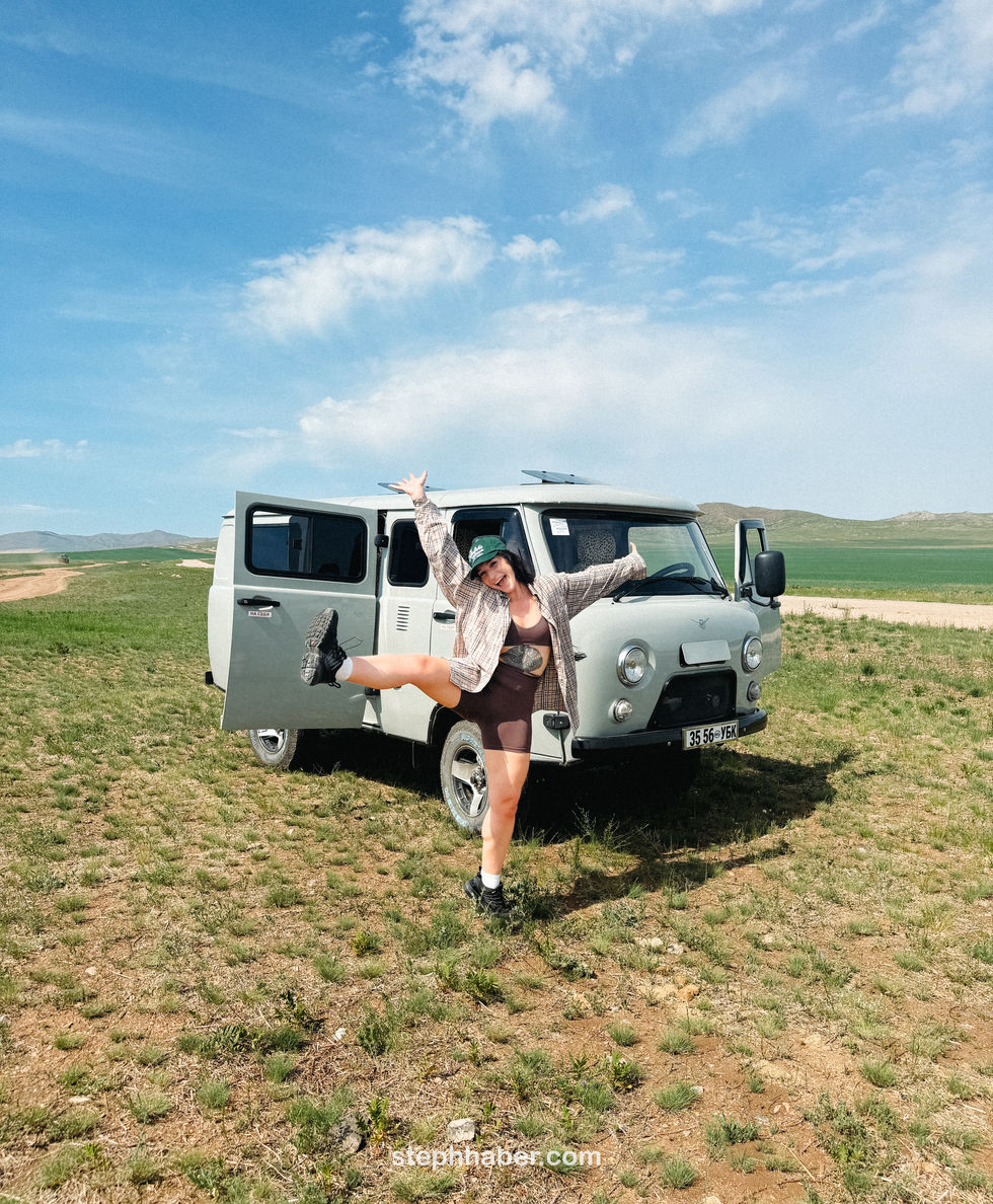 Person joyfully posing in front of a van. Mongolia