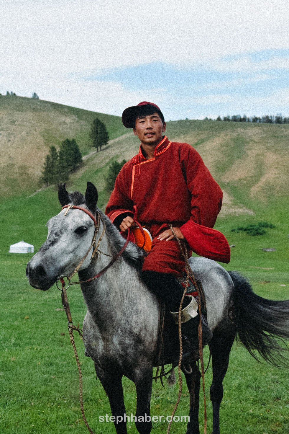 Person in traditional attire riding a horse outdoors. Mongolia