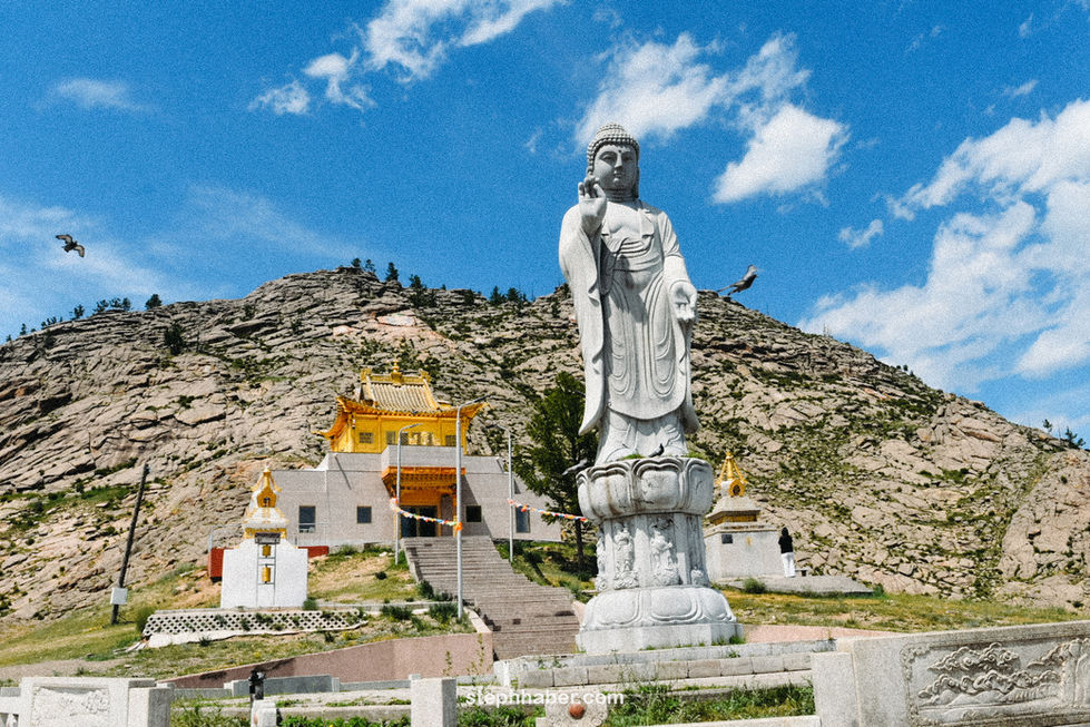 Large statue with mountainous backdrop and temple. Mongolia