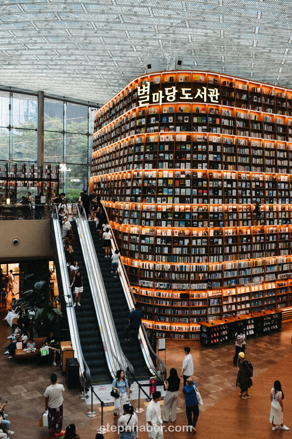 Large library with escalator and towering bookshelves.