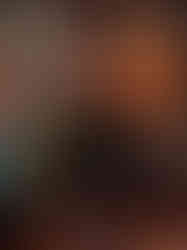 um homem negro, de bigode e cavanhaque, laterais da cabeça raspadas em um corte undercut e vestindo um uniforme militar em um bar