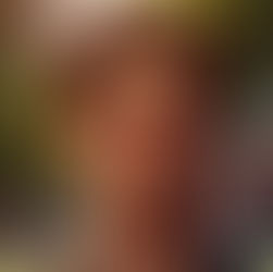 um homem jovem, na casa dos 30 anos, de pele clara, cabelos curtos na cor castanho-avermelhados e olhos âmbar