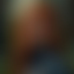 Uma mulher ruiva, de tez clara e olhos azuis, vestindo uma jaqueta de couro preta em uma floresta tropical