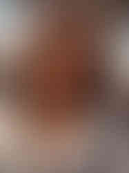 uma mulher iraniana de cabelos cacheados castanhos, vestindo uma jaqueta branca sobre uma regata branca e usando óculos escuros estilo aviador