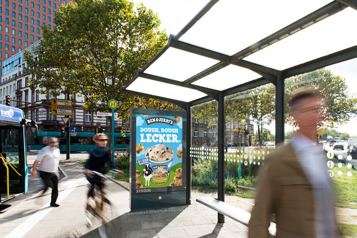Bus stop with a vibrant Ben & Jerry’s poster featuring bold ice cream visuals and striking typography. Set in a lively urban environment with people passing by, the campaign stands out clearly in everyday city life.