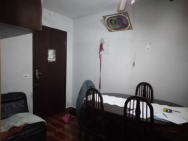 Sala de jantar antes da reforma, com mesa de grandes dimensões, porta de entrada escura e piso escuro no apartamento na Vila Prudente.
