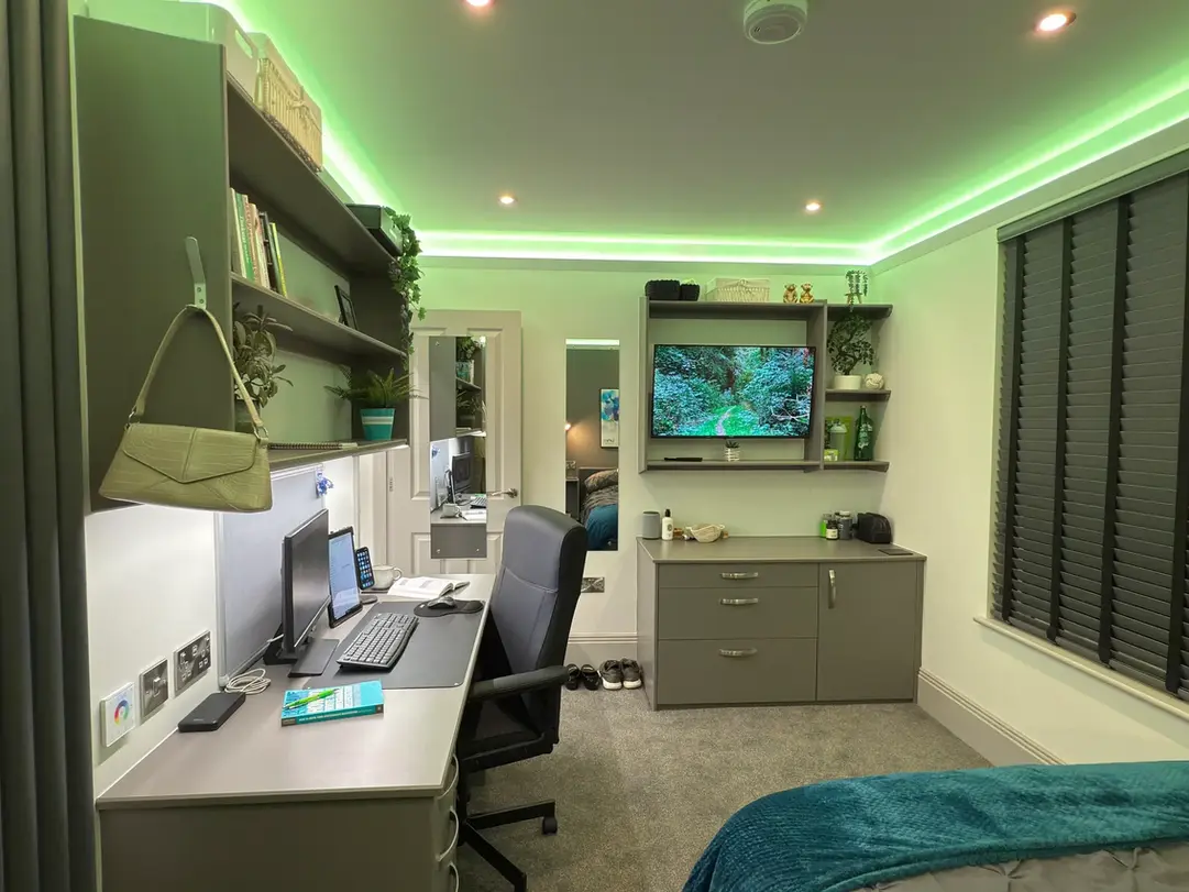 Student bedroom with built-in wardrobe, study desk, LED mood lighting, and wall-mounted TV.