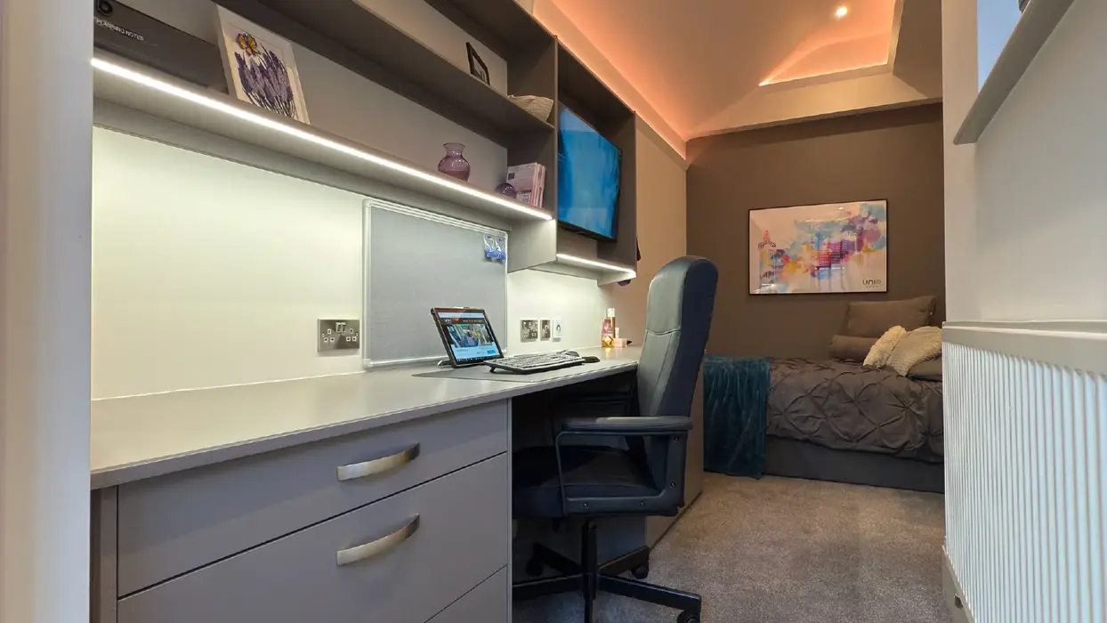 Luxury student bedroom with TV, desk, and integrated shelving under soft LED glow