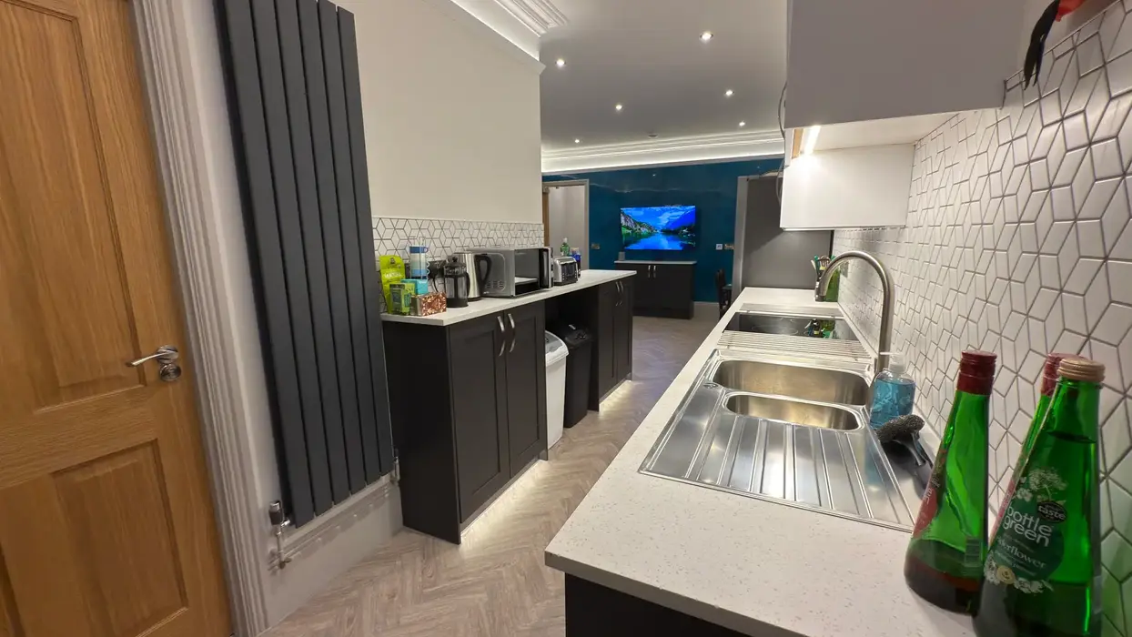 Fully equipped student kitchen with oven, microwave, and ambient ceiling lights.