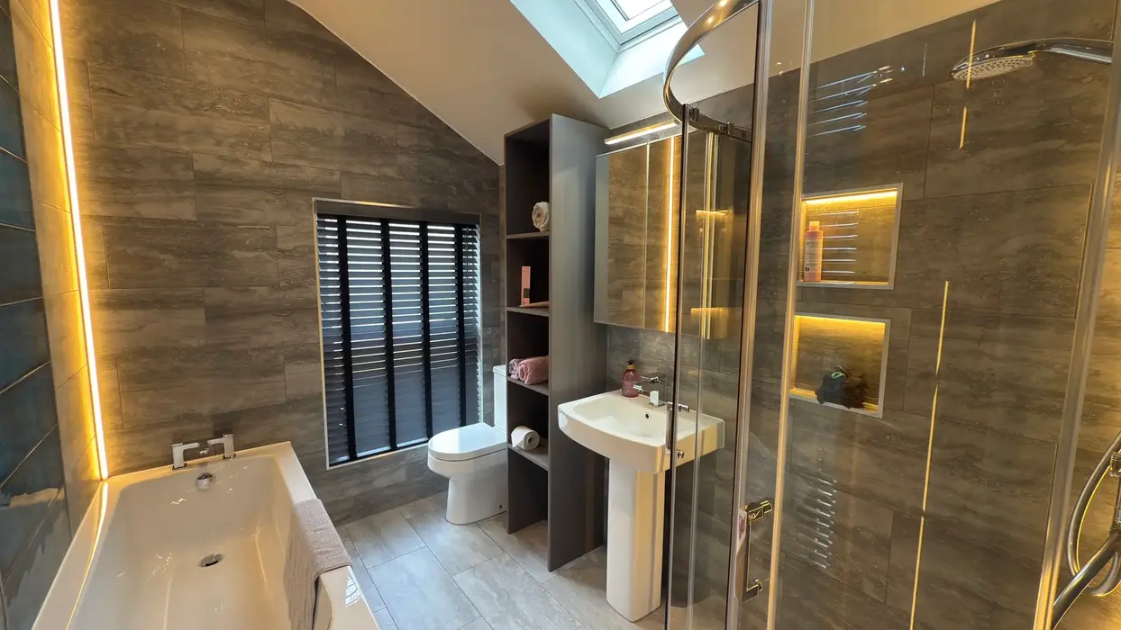 Modern bathroom with walk-in shower, illuminated mirror, and tiled walls.