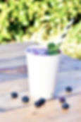 A biodegradable paper cup topped with ice on a wooden table outdoors
