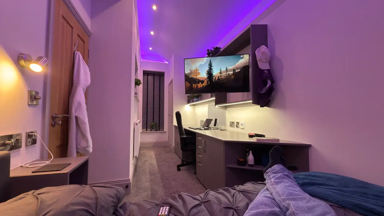 Comfortable student bedroom with ambient lighting and built in workspace.