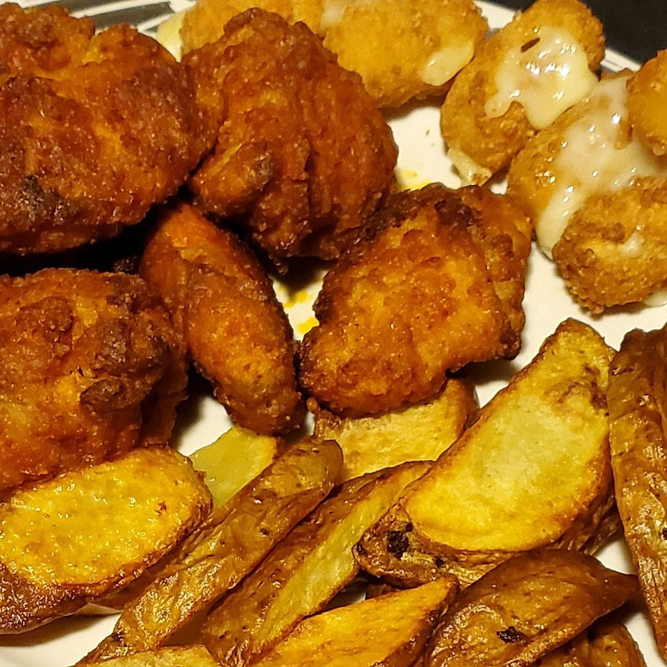 A plate of food with wings, potato wedges and veggie "mozarealla" cheese sticks.