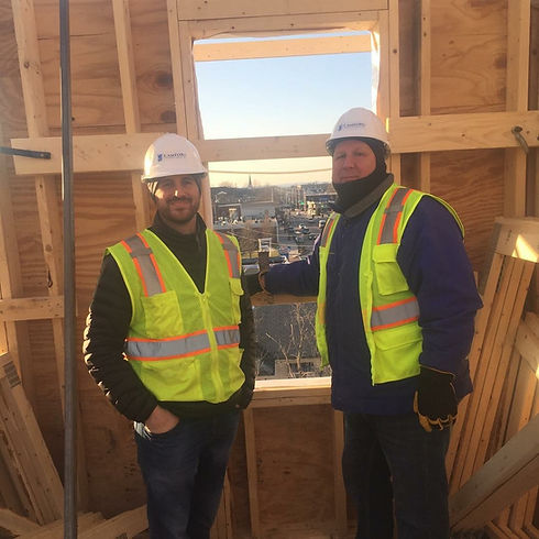Two men in hard hats and safety vests at a construction site