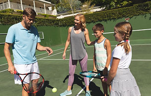 happy-caucasian-couple-with-daughter-son-outdoors-playing-tennis-tennis-court.jpg