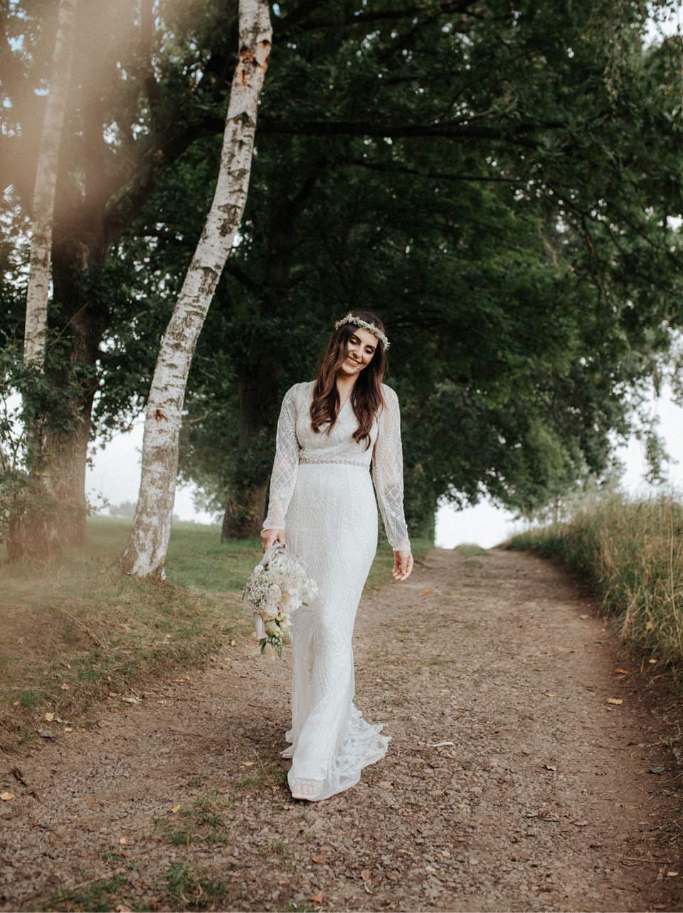 Hochzeitsfotografie, Braut mit Spitzenkleid hält Brautstrauß und lacht