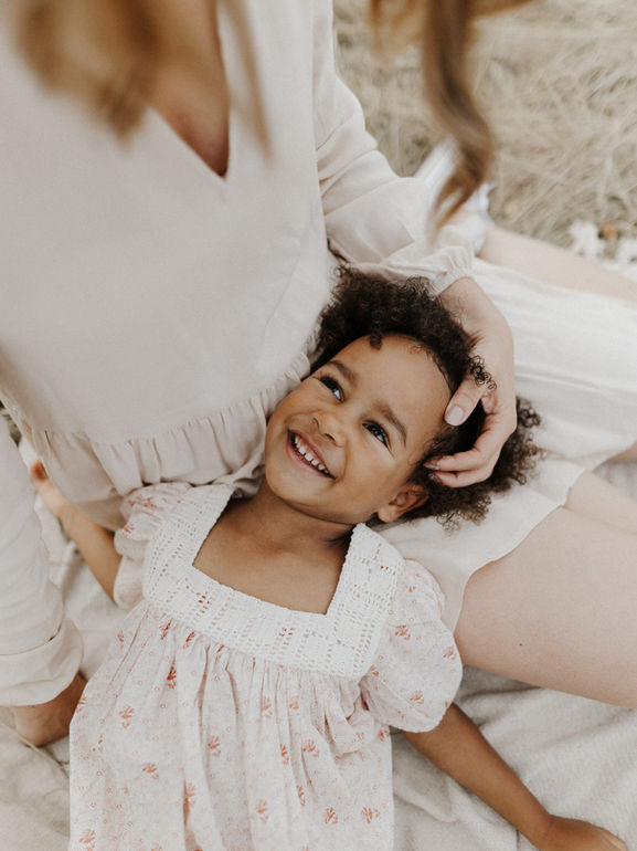 Kinderfotografie, Kind liegt im Schoß der Mutter und lacht sie an