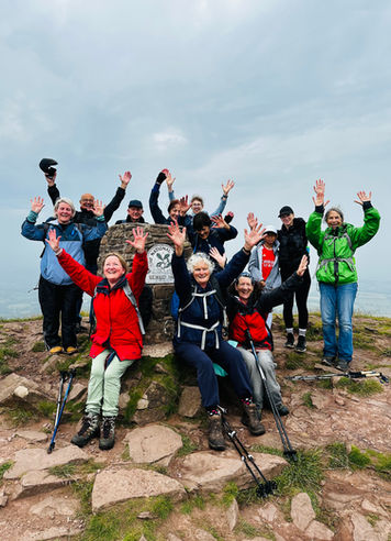 A group of happy walkers gathered round a trigg point