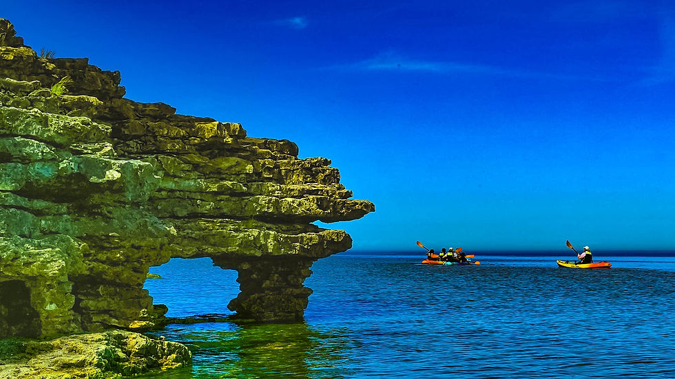 Kayakers paddle past an outcropping at Cave Point County Park in Door County Wisconsin