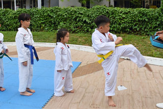 Yellow belt student doing a front kick at Momentum Taekwondo in SG