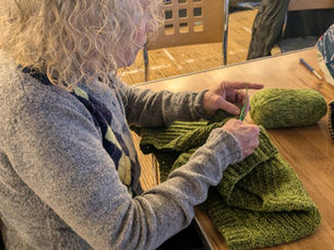 A crocheter making a green jumper
