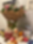 Flowers and toys on a desk with colored boxes, a "Happy Birthday" card, and a wall planner in the background. Cozy, festive scene.