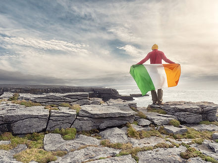 Boy students with Irish flag overlooking Ireland's coastline