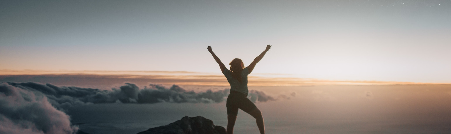 woman-raising-arms-on-mountain-top-2022-
