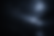 Bare tree branches with small droplets of water, softly lit in near darkness with a blurred, low-light background.