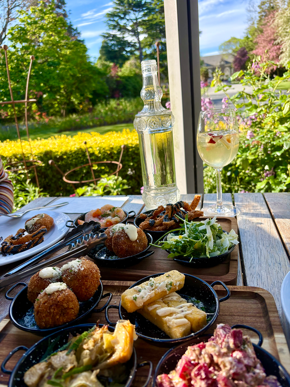 Various tapas on a table in a garden on a sunny day with flowers in the background