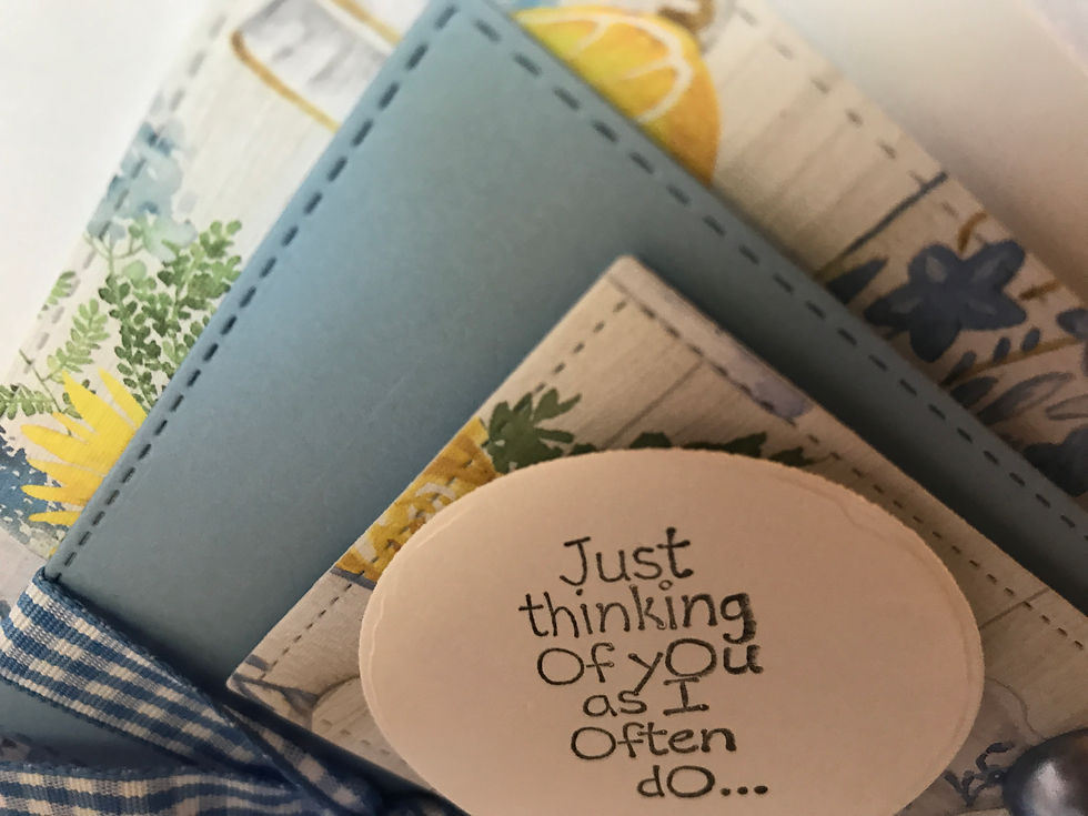 Thumbnail: "Just thinking of you as I often do..." is the sentiment on the cover of this beautiful blue and lemon yellow card.  Set on a white background is a floral blue and yellow print with lemons and china.  Then a blue die cut stitched card stock with another layer of print, and then the sentiment in a white circle.  To the right are three large shinny blue gems and underneath a blue and white gingham ribbon with a pearl and rhinestone center.