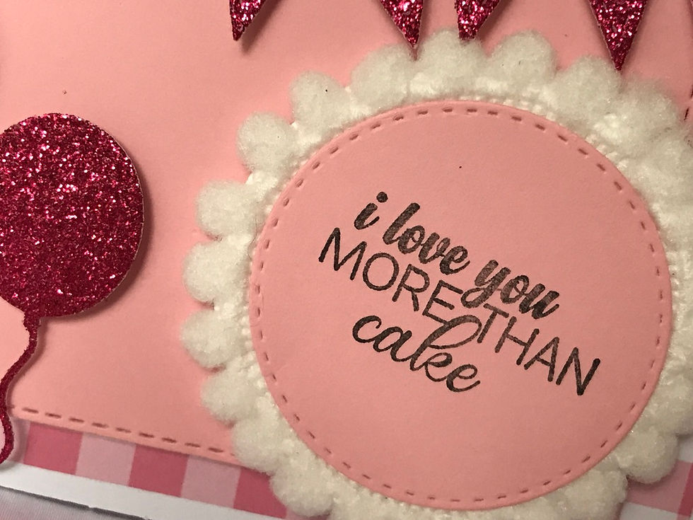 Pink and white checkered background with a pink stitched rectangle die cut.  A pink glitter banner across the top with a pink and floral pink balloon.  Then a bed of white fluffy ball trim and the sentiment, "I love you more than cake."