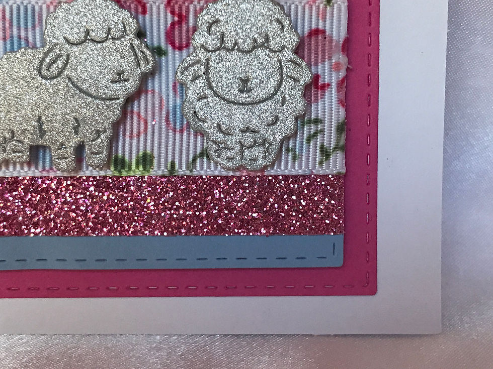 Thumbnail: The Lord is my Shepherd" text in script with silver glitter paper.  Pink and blue background colors with die cut stitching.  A pink glitter ribbon wide enough for another floral ribbon over the center with pink and blue flowers.  Embellished with three glittery silver sheep on the floral ribbon.