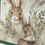 Thumbnail: Forest green paper with coordinating bunny print in a green brushy field.  Very rustic looking, real to life bunnies.  Four wooded buttons on a jute cord with knotted ends.  Jute runs thru the buttons tied in smaller knots.  Then a jute bow tied at the top of the printed bunny paper.