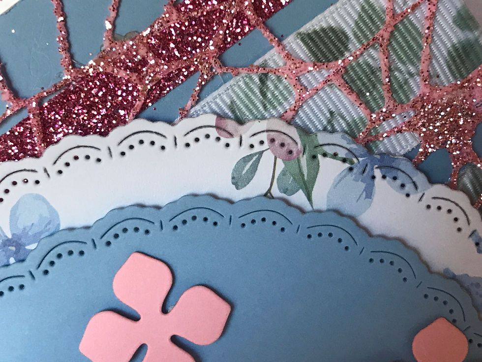 Thumbnail: Beautiful pink hydrangea flowers in the center on two round scalloped circles, one in blue, and one in blue floral.  Two green leaved grosgrain ribbons and two glittery pink ribbons make up the border, with a pink glittery underlay.