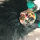 Thumbnail: A teal, black, and white silicone wristlet with a large silver key chain for easy access.  Also a large black furry pom pom with a Dog Mom key chain in silver.