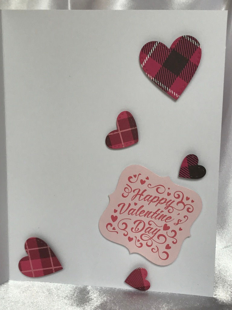 Thumbnail: Pink upside down umbrella with glittery silver handle set upside down on a white heart embossed bed.  The umbrella sits upside down to collect all of the falling hearts in varies shades of pink and white plaid prints.    Behind the white is a pink and then a plaid pink layer of die cut card stock on a white card.