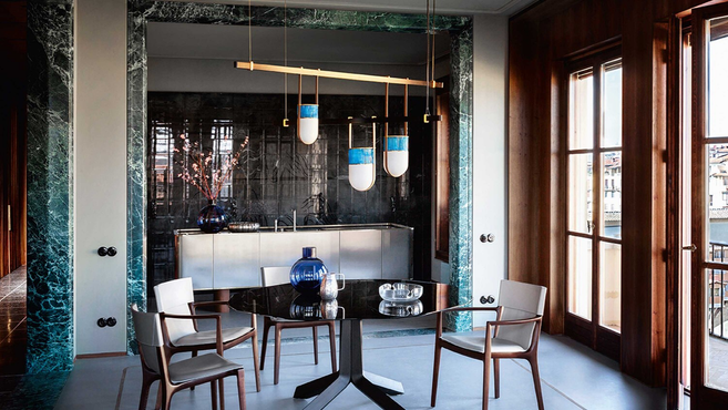 Xi Suspension pendant lamp by Poltrona Frau styled above a dining table with chairs in an elegant interior, highlighting the pendant lighting design within an architectural space