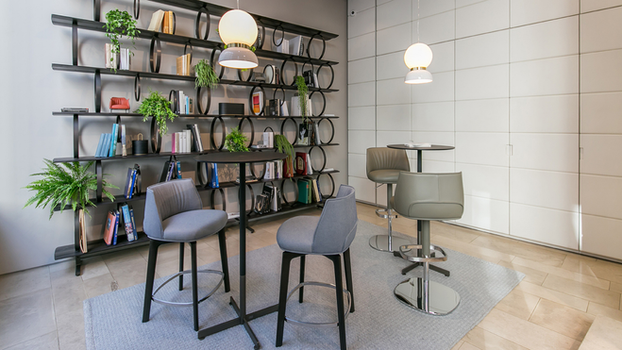 Poltrona Frau Archibald stool with wood base positioned within a refined interior space demonstrating the sculpted seat and elegant designer bar seating form