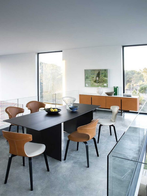 Set of compact armchairs arranged around a dining table, highlighting their sculptural backs and integrated armrests within a contemporary dining environment