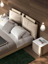 Angled view of the Times bed showing the upholstered headboard and integrated support with neatly arranged bedding