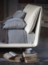 Side corner view of the John-John bed showing the curved headboard and the transition into the upholstered base
